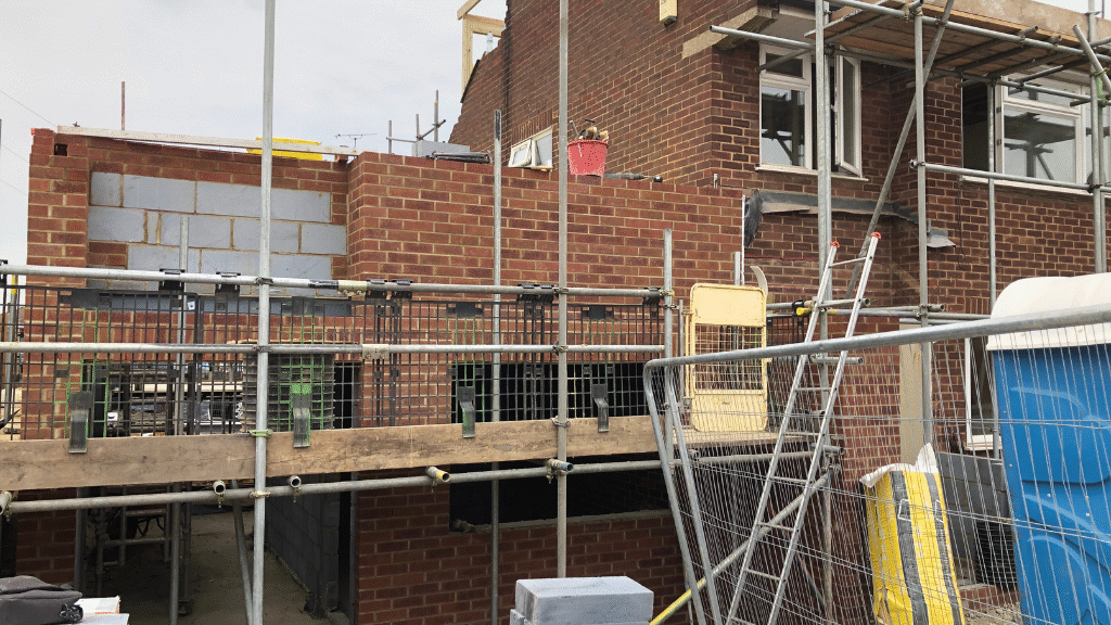 Modern UK home extension showing a mix of red brick and white render exterior, representing rising material costs and construction budgeting.